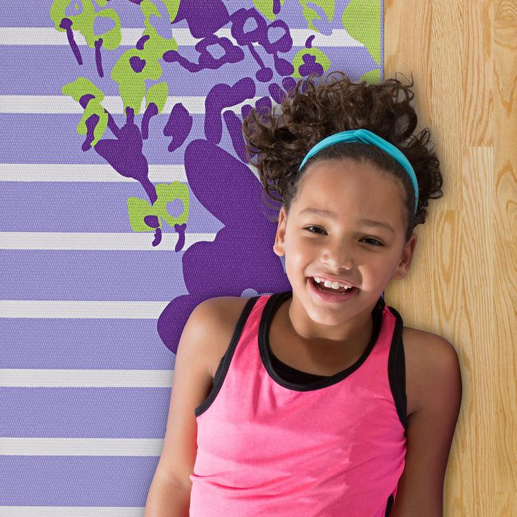 Girl laying on Gaiam Kids Purple Flower Yoga Mat 3 mm