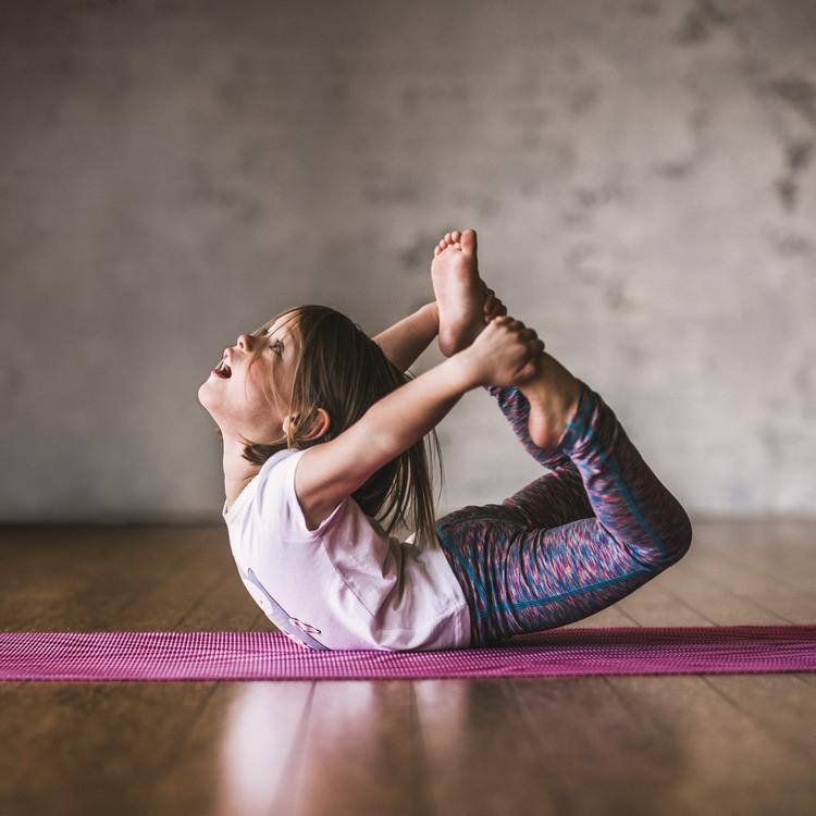 Girl in bow pose on Gaiam Kids Pink Zebra Yoga Mat 3 millimeters
